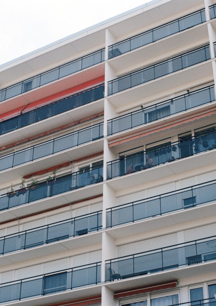façade d’immeuble aux balcons vitrés, une bande rouge