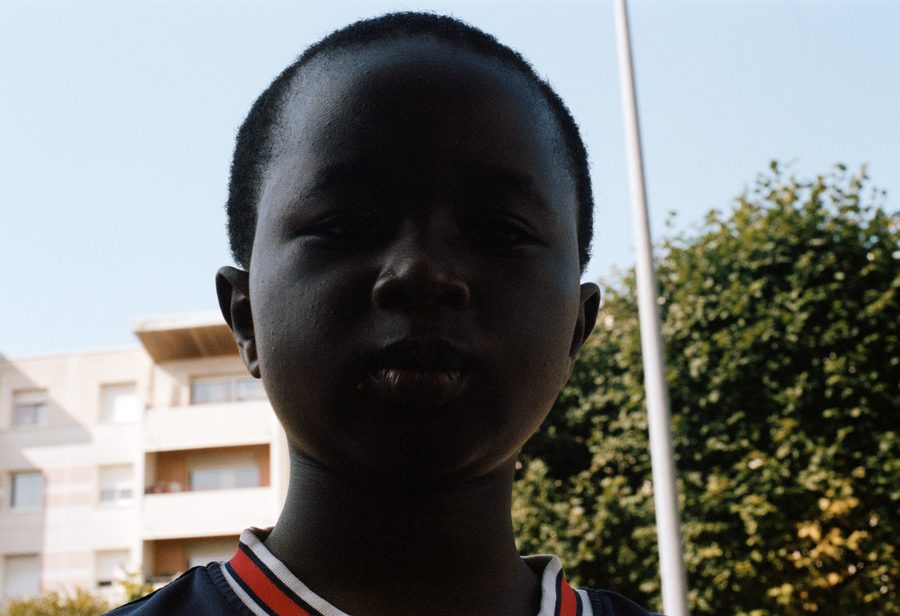 portrait d’un garçon en contre-jour devant les immeubles