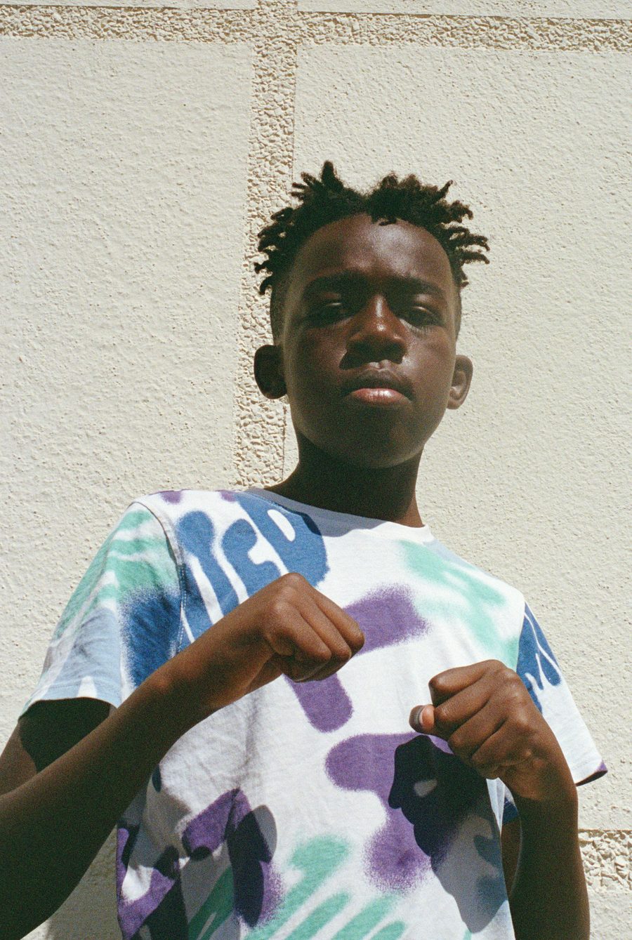 un garçon en t-shirt tie-and-dye, les poings serrés