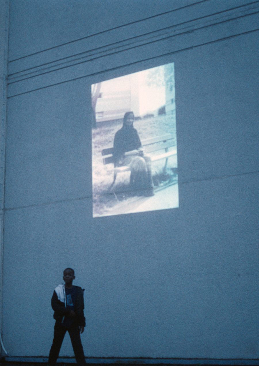 une silhouette devant la projection d’un portrait sur la façade