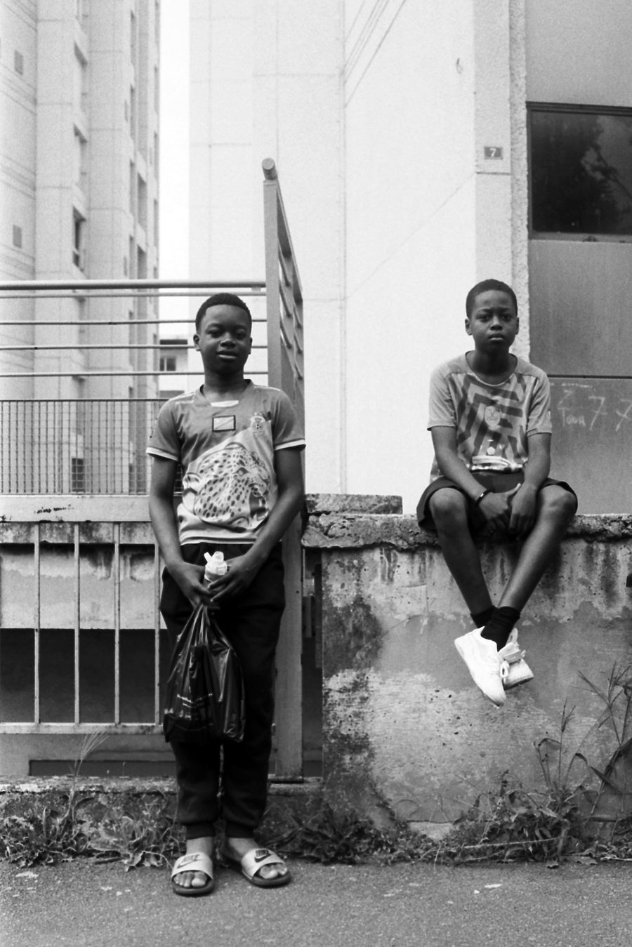 deux garçons assis sur un muret, portrait en noir et blanc