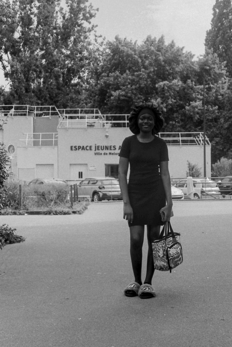 une femme marche devant l’Espace Jeunes, noir et blanc